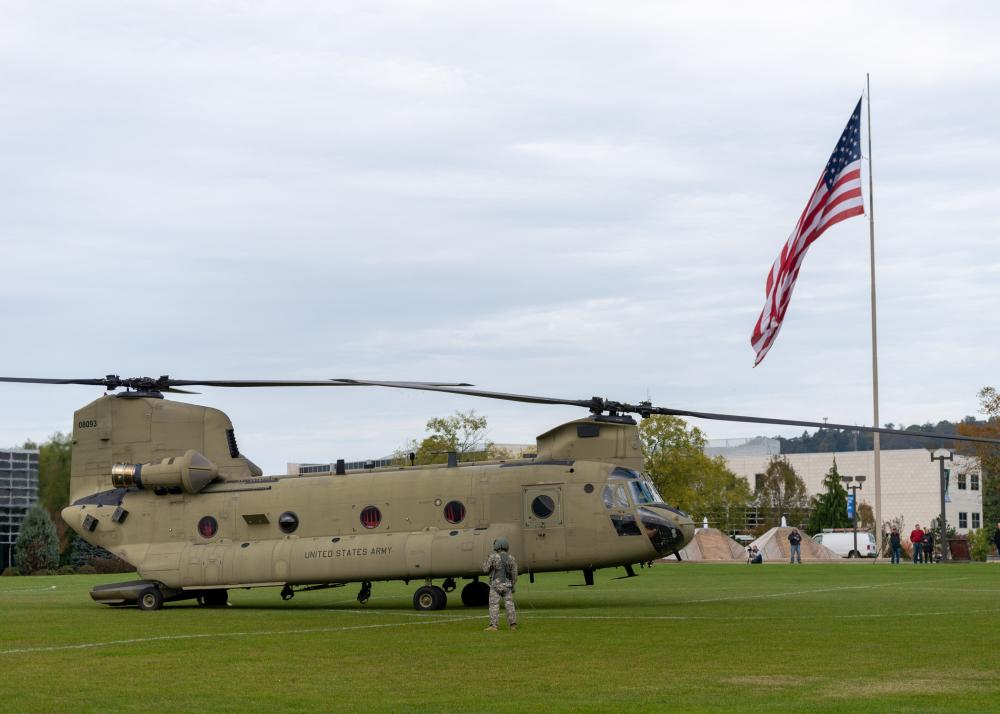 A U.S. Army helicopter parked at Penn College, with an American flag flying nearby.