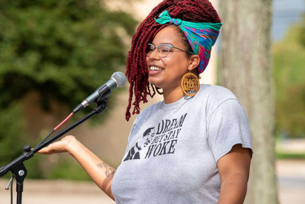  Tiana Rawls-White addresses an out-of-frame crowd at a microphone