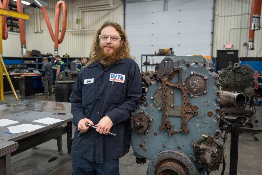 Jake Dame, Bus Tech Apprentice leaning against equipment