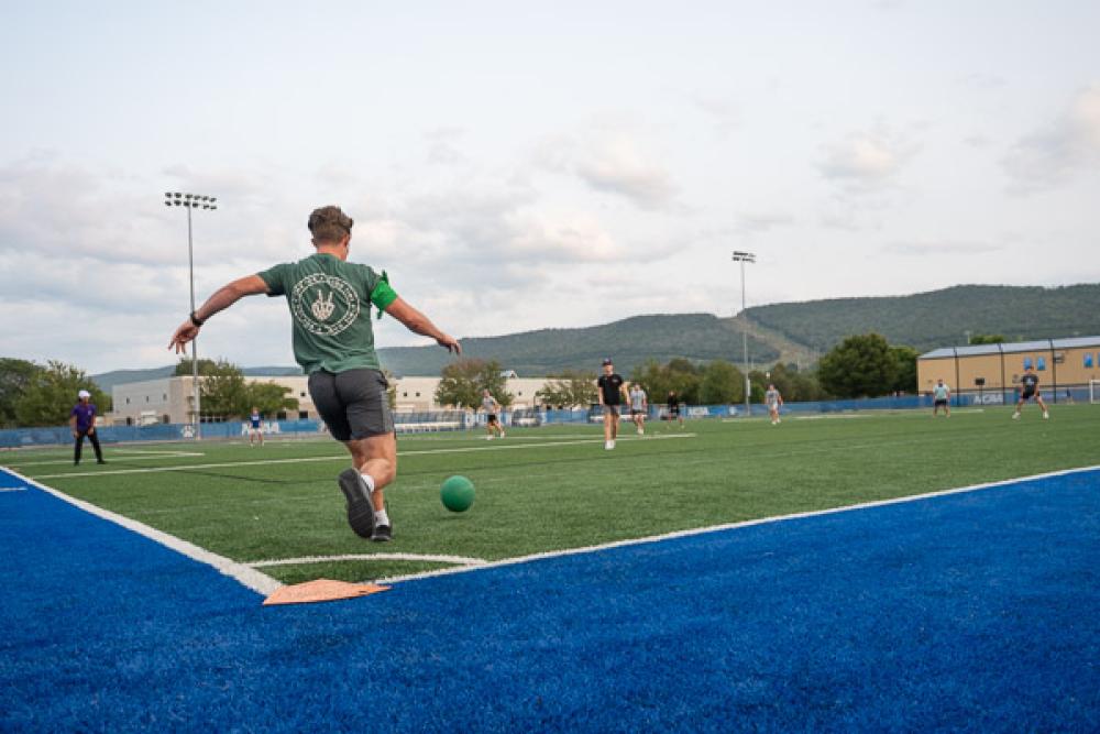 A student kicking a ball on a field.
