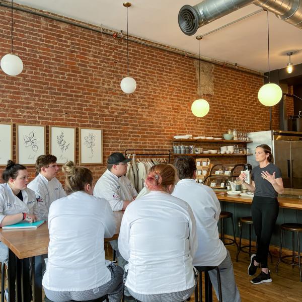 Carnie Datres speaks with students at her downtown business, Kitchen Repose.