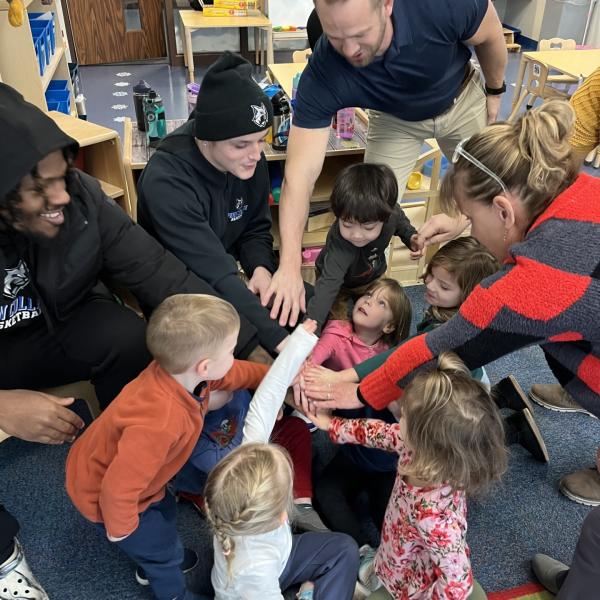 The coach adds his hand to a Wildcat huddle.