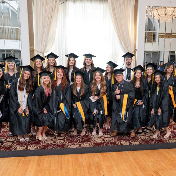 A large group of men and women in black graduation caps and gowns.