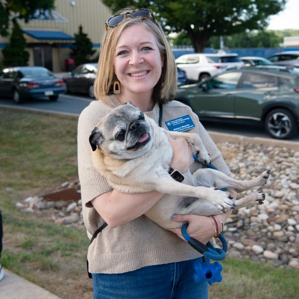 A woman holds a pug in her arms.