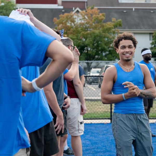 A student in a blue shirt smiles at the camera.