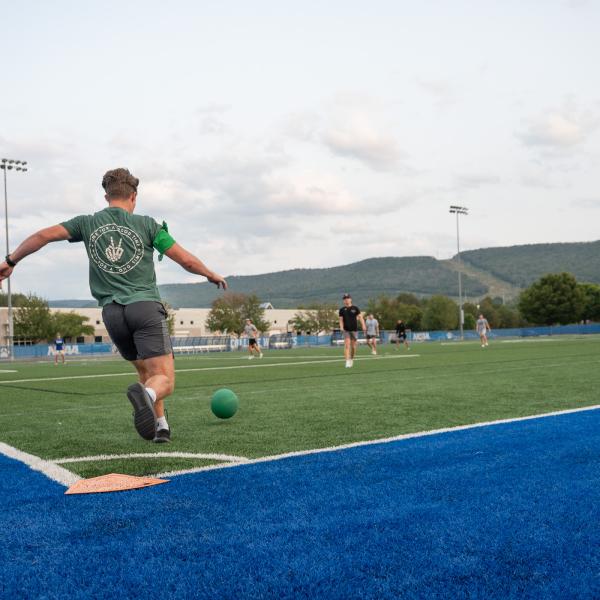 A player in green prepares to kick a kickball.