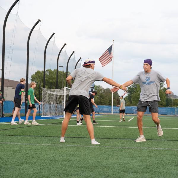 A student reaches out for a hand slap as another student runs by.