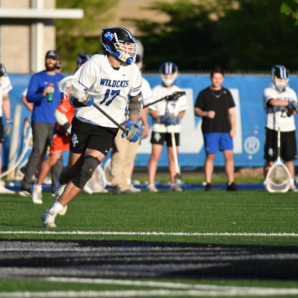 A lacrosse player, in uniform, runs on UPMC field during a game.