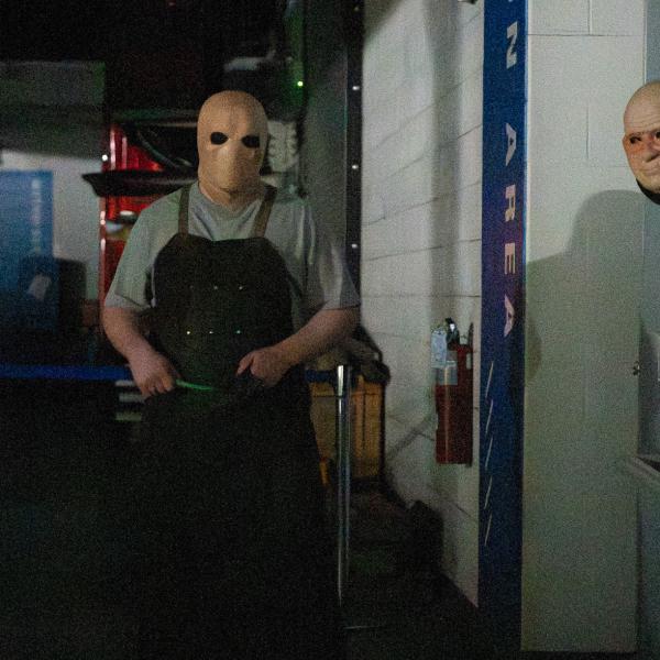 Students in scary masks in a dark room.