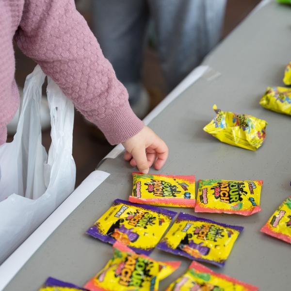 A child's hand reaches for candy laid out on a table.
