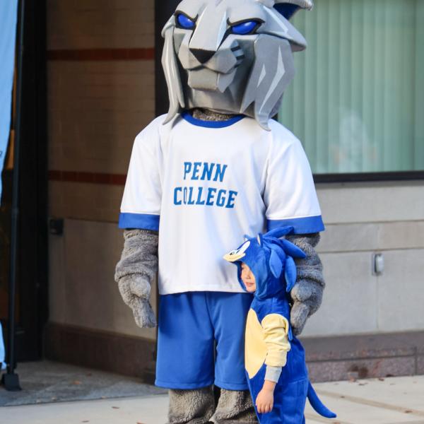 The Wildcat mascot stands next to a child in a Sonic the Hedgehog costume. Behind them is the Journey Bank Community Arts Center.