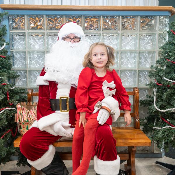 A child in a red dress sits on Santa's lap in Penn's Inn.