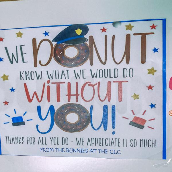 A box of donuts with a printed sign that reads: We donut know what we would do with you! Thanks for all you do. We appreciate it so much! From the Bunnies at the CLC."