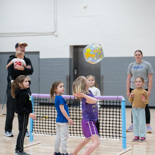 Girls bat a beach ball over a small net.
