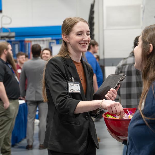 A student in a suit reaches into a bowl of candy offered by an employer.