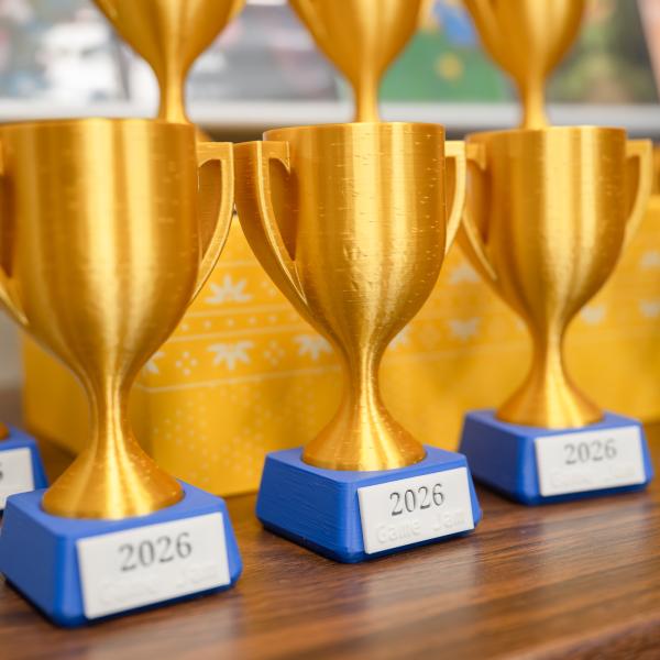 Trophies with blue bases, shiny gold-colored cups and small plaques that say "2026 Game Jam."