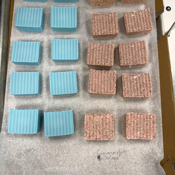 Eight blue and eight brown hand-cut bars of soap sit on a parchment-lined baking tray.