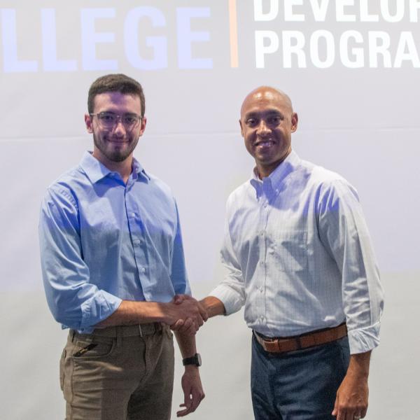 Two men in business attire shake hands.