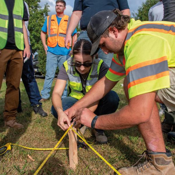 Residential construction technology & management students Cassandra Guiffre and Nick DeRemer take measurements as they mark the boundaries for the home.