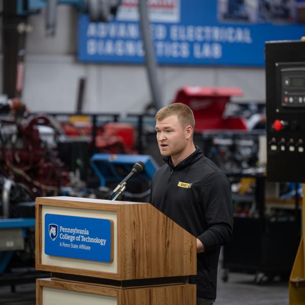 A man speaks from behind a lectern in Penn College's on-site power generation lab.