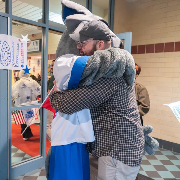 A man hugs Penn College's Wildcat mascot.