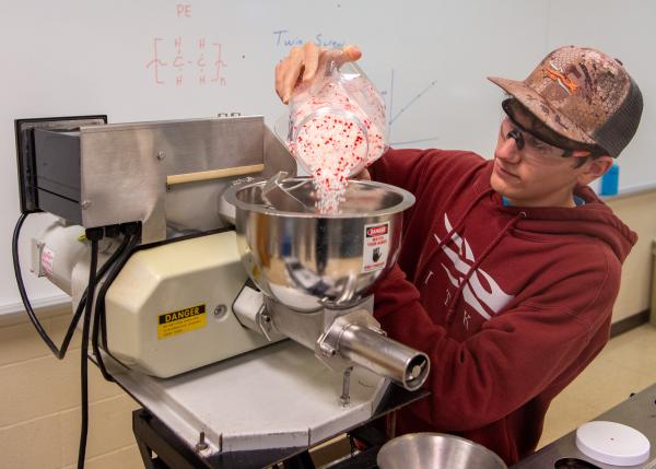 student preparing a machine for polymer processing