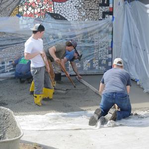 Alongside a tarp to protect the building's Centennial-era mosaic, the crew smooths the freshly poured surface.