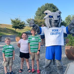 Thee children stand next to Penn College's Wildcat mascot.