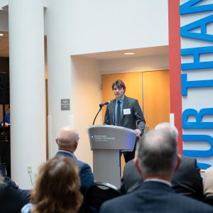 A student in a suit stands behind a podium