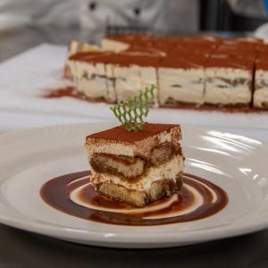 A plated piece of cake with a thin, green lattice cookie inserted in the top.