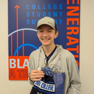 A student holds a gift bag and a knitted cap.