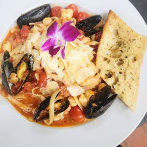 A plate of food that includes mussels, pasta and tomatoes.
