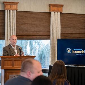 A man speaks from behind a podium inside Le Jeune Chef Restaurant.