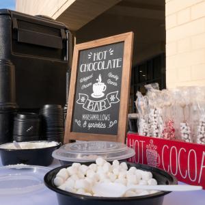 A "hot choocolate bar" with a caraffe of hot cocoa, cups, marshmallows, and other hot chocolate toppings.