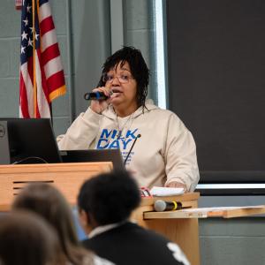 A woman stands behind a podium and sings into a microphone.