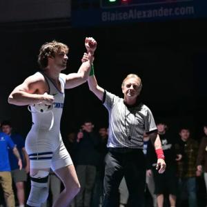 A referee holds up the arm of Nick Woodruff after he wins a match.