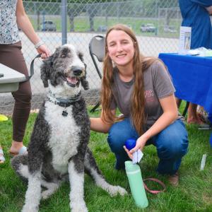 A student kneels next do a dog.