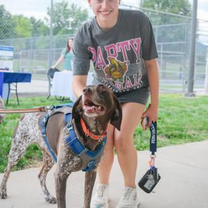 A woman holds a medium-sized dog's leash.