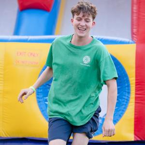 A smiling student walks away from an inflatable obstacle course.