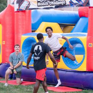Smiling students exit a brightly colored inflatable obstacle course.
