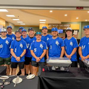 Eleven students wearing Penn College baseball jerseys pose behind a line of tables in black tablecloths in the college's Keystone Dining Room.