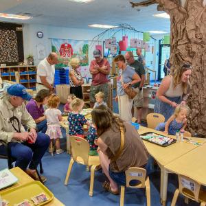 Adults and children gather in a preschool classroom.