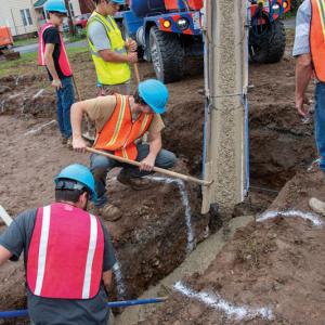 Students in a Concrete Construction class pour the home’s footer.