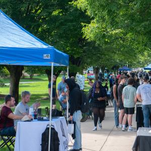 Students gather around tables that line a Penn College walkway.