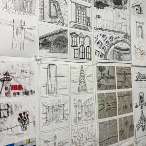 A wall is covered by 5-inch-by-five-inch architecture-related sketches.