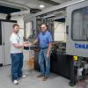 A student and a faculty member stand in front of a Bihler 4 Slide-NC metal stamping and forming center.
