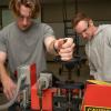 Two students work on a piece of plastics extrusion equipment.