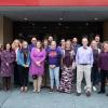 A group of people wearing purple clothing gathers on the Lifelong Education Center patio.