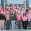 A group of students and employees wearing pink stands on the steps of Penn College's Advanced Technology & Health Sciences Center.