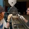 Two students interact with a plastics extrusion machine.